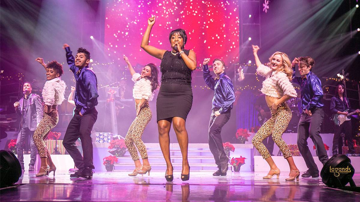 Aretha Fraklin impersonator performing on stage with back up dancers and musicians at Legends in Concert in Myrtle Beach, South Carolina, USA